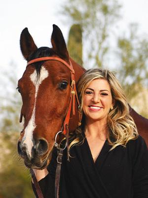 Madison Florence, equine studies graduate standing next to a horse.