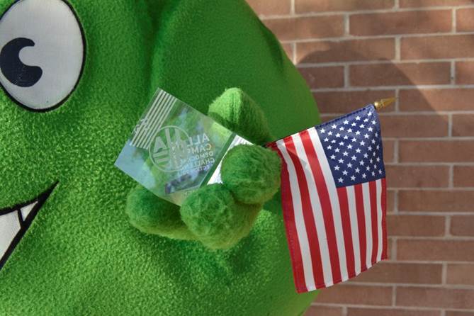 SCC mascot Artie holding a civic engagement award and an American flag.
