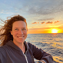 A woman with red hair with sunset in background out on sea