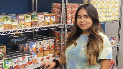 student standing in front of stocked shelves in the food pantry