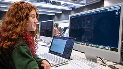 Student working in classroom using laptop and desktop computers