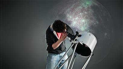 student looking through a telescope at night sky