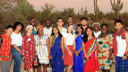 A diverse group of International Exchange students posing for a photo in the desert.