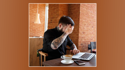 man covering eyes while looking at laptop