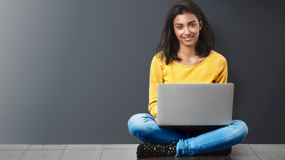 student sitting on wood floor holding laptop