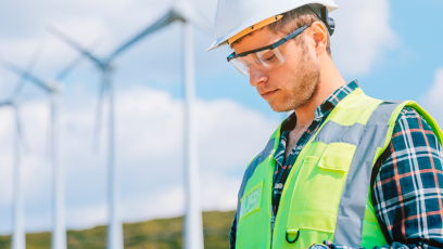 sustainability officer looking at clipboard with wind power turbines in background