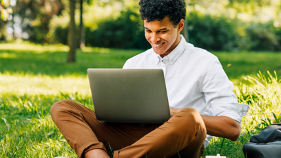 student studying outside on campus with laptop