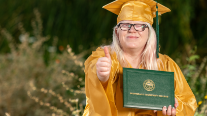 older adult graduate holding diploma and indicating happiness with a thumbs up
