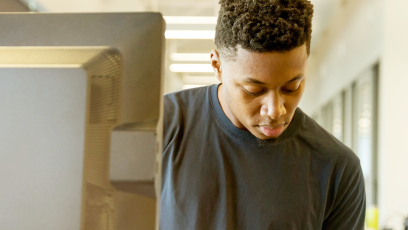 Young man making notes by a computer