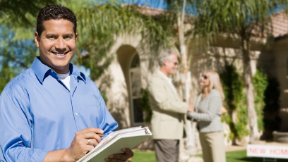 smiling realtor with happy couple in background outside new home