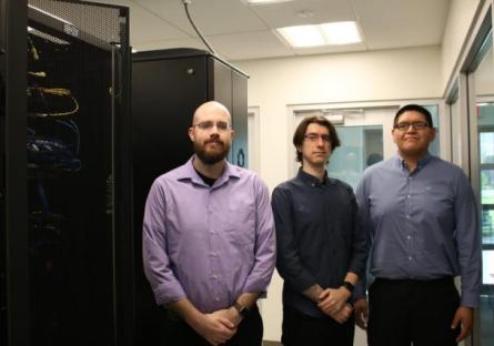 Kevin Buffington, Tim Olson, and Anthony Jordan are posing in a server room. They are wearing business casual clothing.