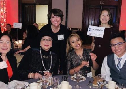 A photo of Stephanie Fujii at a ceremony posing with a group of other professionals.