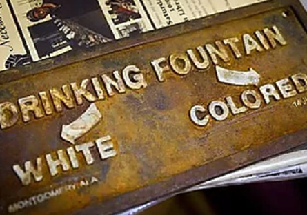 Metal sign that separates races at a drinking fountain Sign that states: Drinking Fountain - White - Colored