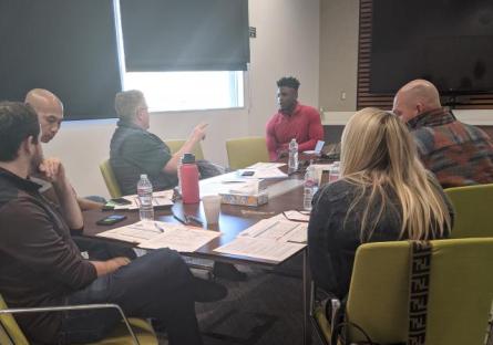 A room full of judges reviewing Little Pitch contestant materials.