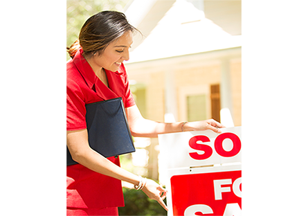 Real Estate agent holding a sold sign 