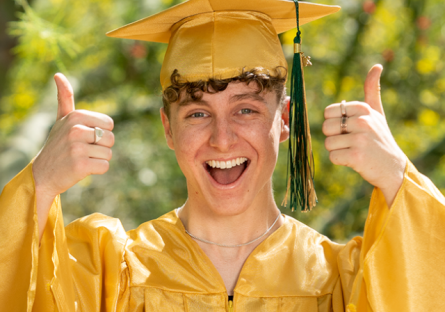 SCC Graduate smiling graduate with two thumbs up