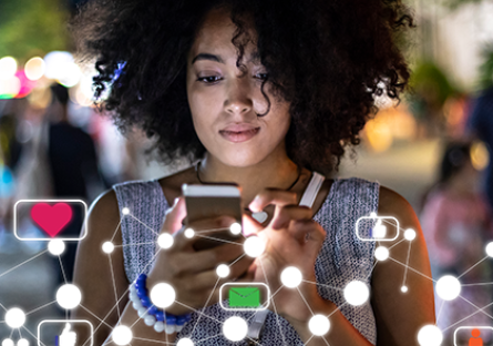 female student gazing intently at mobile device while coding