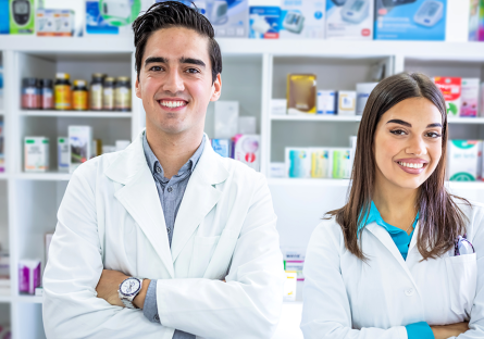 male and female pharmacy technicians in a pharmacy with pills on shelves behind them
