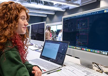 Student working in classroom using laptop and desktop computers