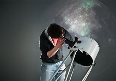 student looking through a telescope at night sky