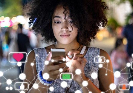 female student gazing intently at mobile device while coding