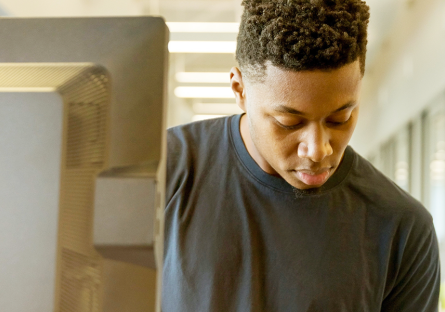 Young man making notes by a computer