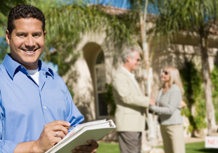 smiling realtor with happy couple in background outside new home