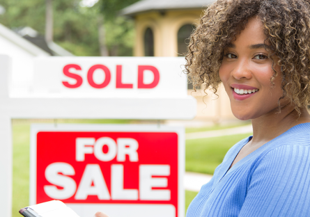 realtor in front of for sale sign with sold placard