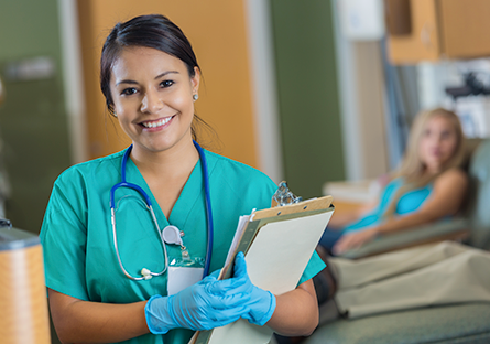 nurse holding clipboard with blurred background of patient in hospital bed
