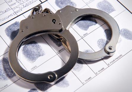 Handcuffs on a piece of paper with a collection of fingerprints