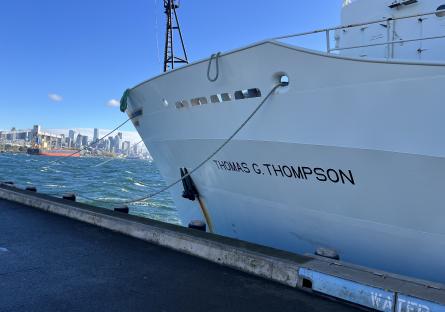 A white boat docked with the name "Thomas G. Thompson" imprinted on it's hull