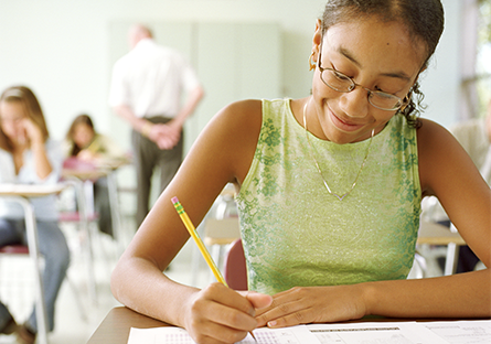 student writing on paper in classroom