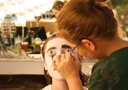 theatre student carefully applying makeup to another student