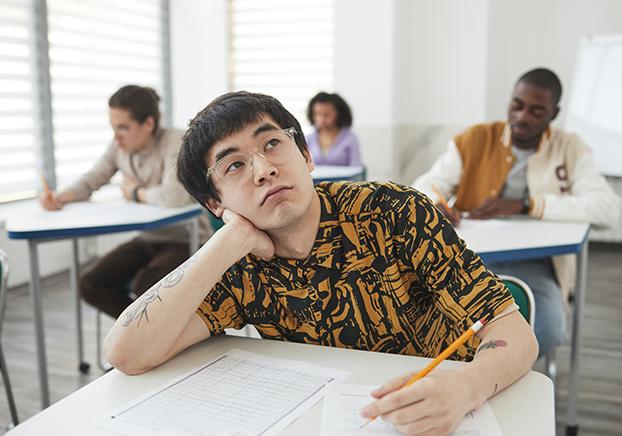 student in class propping head on hand and staring up in a contemplative manner