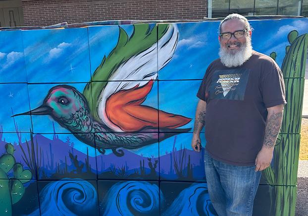 man standing next to a painted wall