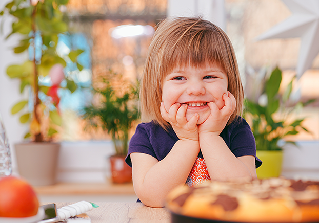 young child resting chin in hands with elbows on the table