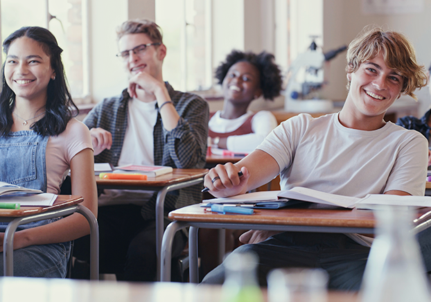 happy students at desks in a classroom setting