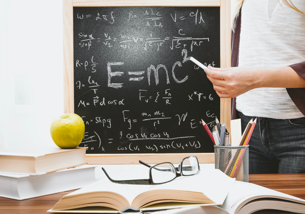 teacher holding chalk and writing formulas on a chalkboard