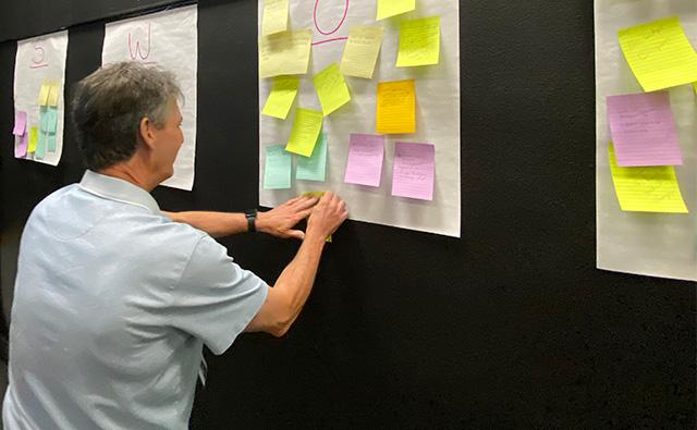 employee adding post-it note to wall